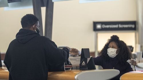 Wearing personal protective equipment, Delta Air Lines customer service agent Kim Franklin (right) communicates with a customer at a Delta Air Lines service desk inside Atlanta’s Hartsfield-Jackson International Airport. (ALYSSA POINTER / ALYSSA.POINTER@AJC.COM)