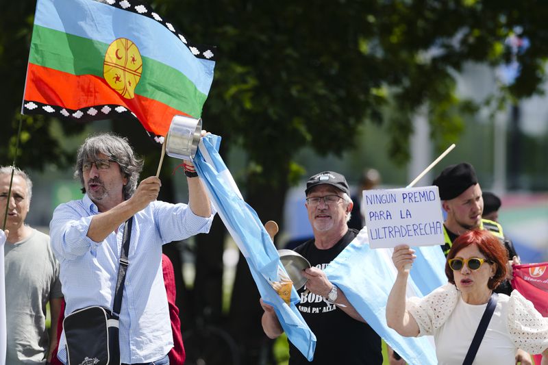 Demonstrators show banners and posters as they protest against the visit Argentina's President Javier Milei for a meeting with German Chancellor Olaf Scholz in Berlin, Germany, Sunday, June 23, 2024. Banner reads: Milei for the hand, no to the base law. Poster reads: 'No allowance for the ultra right wing'. (AP Photo/Markus Schreiber)