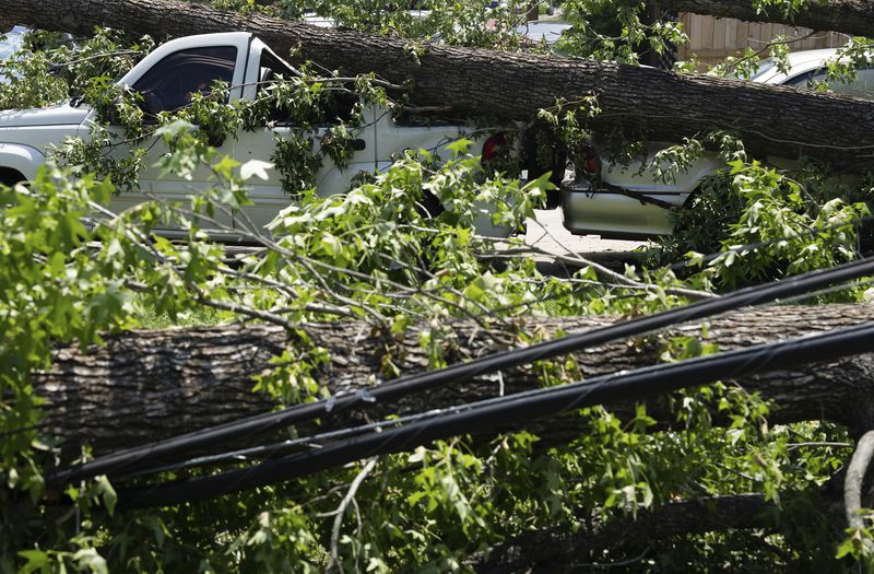 Tree branches that fell during Hurricane Beryl took down power lines and a Jeep in Acres Homes in Houston, on Wednesday, July 10, 2024. ( Elizabeth Conley/Houston Chronicle via AP)
