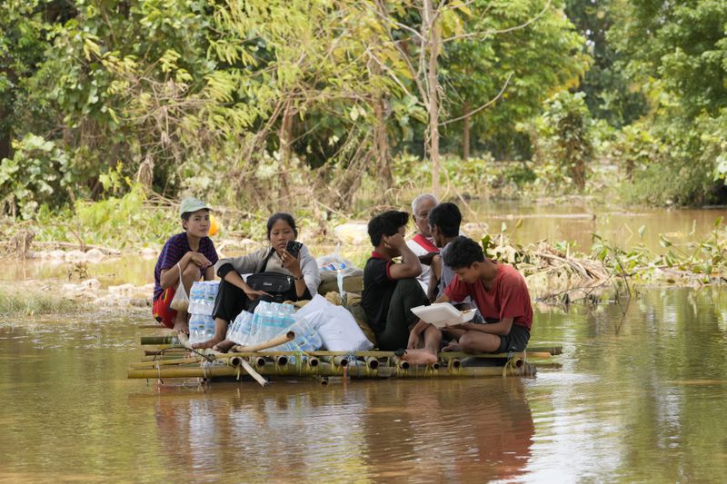 Flood victims rest on a bamboo raft with their food on a flooded road in Naypyitaw, Myanmar, Saturday, Sept. 14, 2024. (AP Photo/Aung Shine Oo)