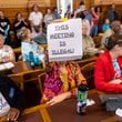 An attendee holds a sign that says “This Meeting is Illegal” during a hastily planned State Election Board meeting July 12 at the Georgia Capitol in Atlanta. (Arvin Temkar / AJC)