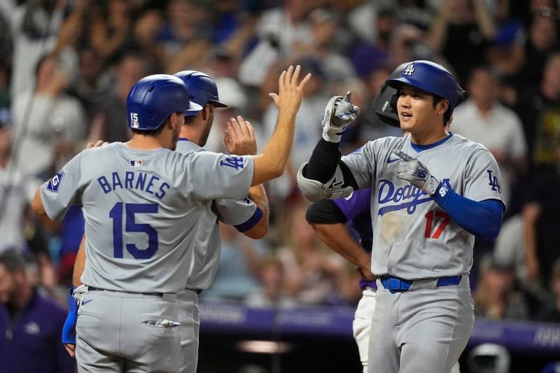 Los Angeles Dodgers' Austin Barnes (15) congratulates Shohei Ohtani (17) who crosses home plate after hitting a three-run home run off Colorado Rockies relief pitcher Anthony Molina in the sixth inning of a baseball game Friday, Sept. 27, 2024, in Denver. (AP Photo/David Zalubowski)