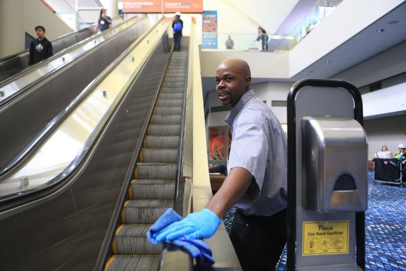 Dion Smith wipes down the escalator during the Construction Education Foundation of Georgia career expo on Thursday, March 12, 2020, at the Georgia World Congress Center in Atlanta. This year, because of the new coronavirus, additional safety measures were implemented. (Christina Matacotta for The Atlanta Journal-Constitution).