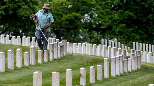 Greg Weber trims along the rows of headstones at the Marietta National Cemetery, located at 500 Washington Avenue in Marietta, on Thursday in preparation for Memorial Day weekend. (John Spink/AJC)