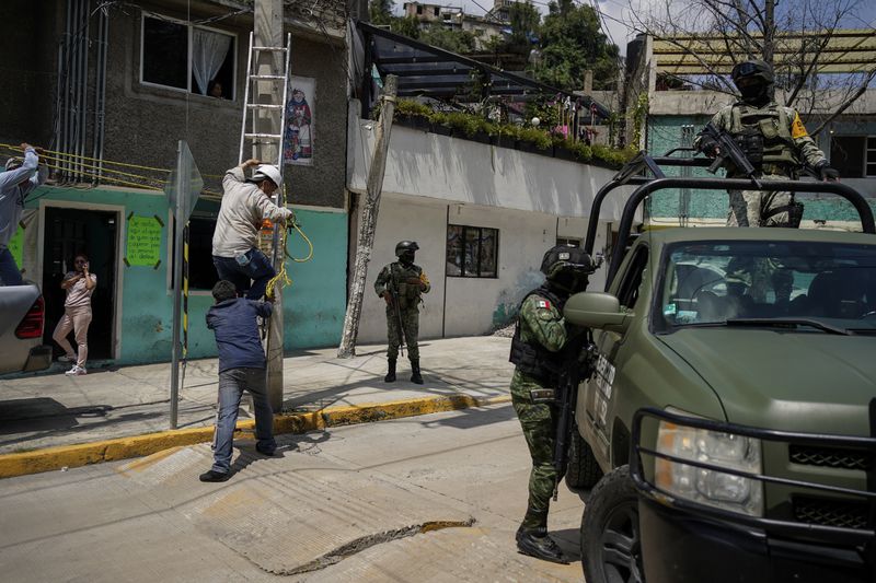 Soldiers guard the area where various people died after a rain-induced landslide, in Naucalpan, Mexico, Tuesday, Sept. 17, 2024. (AP Photo/Felix Marquez)