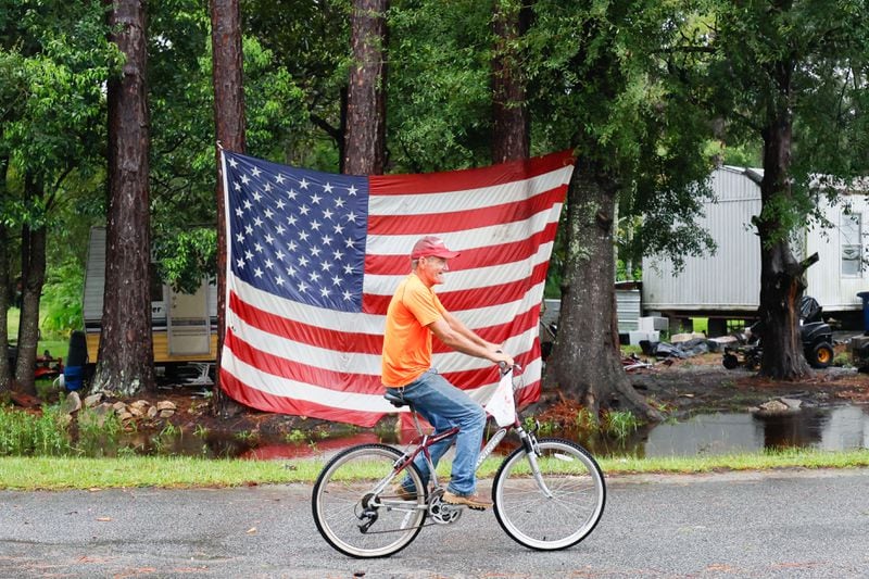 George Smith, 67, rides his bike in front of an American flag at his trailer home in Homersville. Debby did little damage in the area.