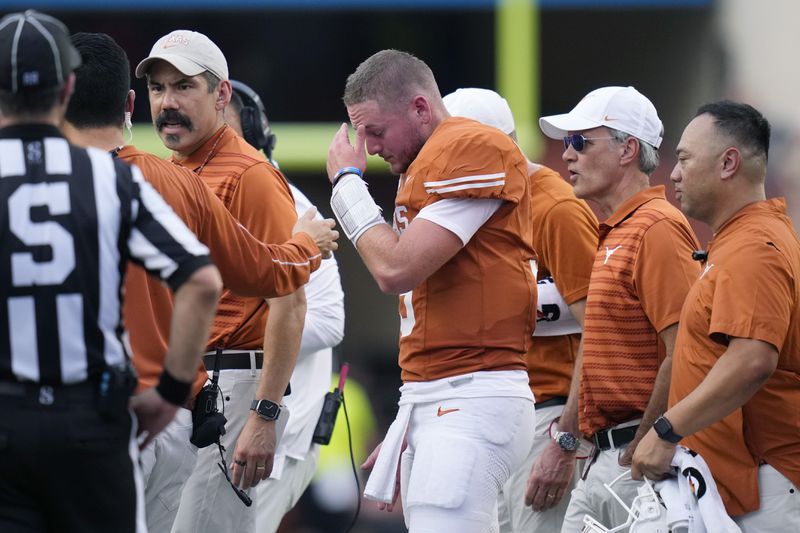 Texas quarterback Quinn Ewers, center, is helped off the field after an injury during the first half of an NCAA college football game against UTSA in Austin, Texas, Saturday, Sept. 14, 2024. (AP Photo/Eric Gay)