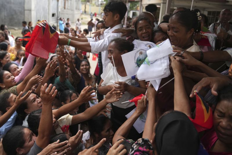 Church officials distribute East Timorese flags and those with a portrait of Pope Francis, after a Sunday Mass ahead of the pope's visit to East Timor, in Dili, Sunday, Sept. 8, 2024. (AP Photo/Dita Alangkara)