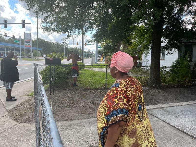 Jacksonville residents Patrick Sapp (left to right) Ron-reco Harris and Crecie Washington look at the police tape surrounding the Dollar General in their neighborhood on Sunday, August 27, 2023.