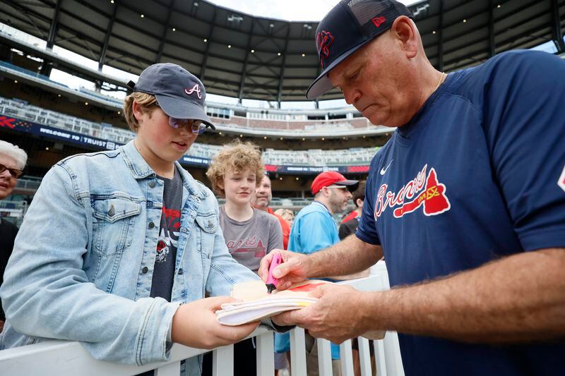 Braves manager Brian Snitker autographs a towel for Mac Hoober, a dedicated fan who traveled with his family from Nashville, Tennessee, to attend the game. Sunday, May 28, 2023. Miguel Martinez / miguel.martinezjimenez@ajc.com 