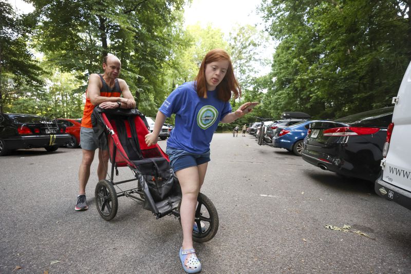 Darden Glass steps out of a running stroller after after a training run with her dad David Glass at the Cochran Shoals Trail. The Glasses will be the first father-daughter duo to race in the competitive push-assist division of the AJC Peachtree Road Race. (Jason Getz / Jason.Getz@ajc.com)