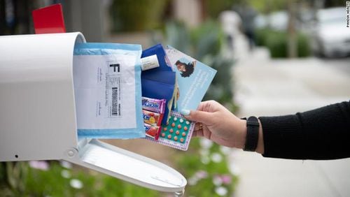 Image shows a mailbox with a white hand reaching in to grab several pieces of mail, including a package of birth control pills.