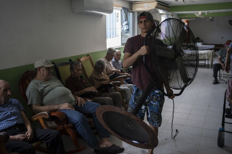 Humanitarian worker Roger Duvan Lagunes carries a fan into the Cogra, an elderly shelter, in Veracruz, Mexico, on June 16, 2024. Human-caused climate change intensified and made far more likely this month's killer heat with triple digit temperatures, a new flash study found Thursday, June 20. (AP Photo/Felix Marquez)