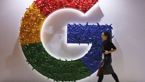 FILE - In this Nov. 5, 2018 file photo, a woman walks past the logo for Google at the China International Import Expo in Shanghai. Google is dropping plans to eliminate cookies from its Chrome web browser, making a sudden U-turn on four years of work to phase out the technology that tracks users for ad purposes. (AP Photo/Ng Han Guan, File)