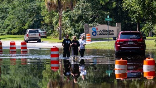 People walk through a flooded road on Bradley Boulevard on Aug. 12 in Savannah. (Katelyn Myrick/The Atlanta Journal-Constitution)