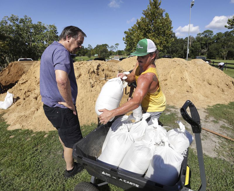 Residents Dennis Lusby, left, and John Guerra fill sandbags at the Orange County distribution site at Barnett Park in Orlando, Fla., Tuesday, Sept. 24, 2024, ahead of the forecast for the possibility of heavy rains in Central Florida. (Joe Burbank/Orlando Sentinel via AP)