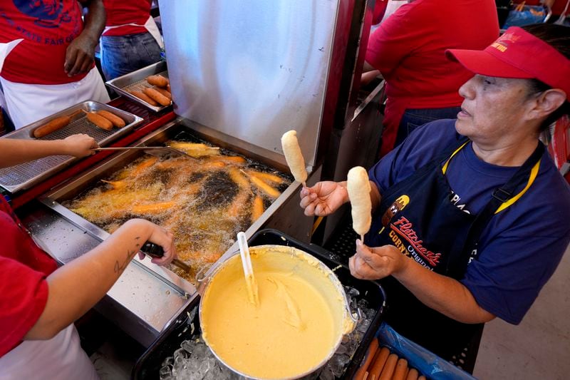 Luisa Lopez, right, helps prepare dozens of Fletchers corny dogs at their food booth at the State Fair of Texas in Dallas, Friday, Sept. 27, 2024. (AP Photo/Tony Gutierrez)