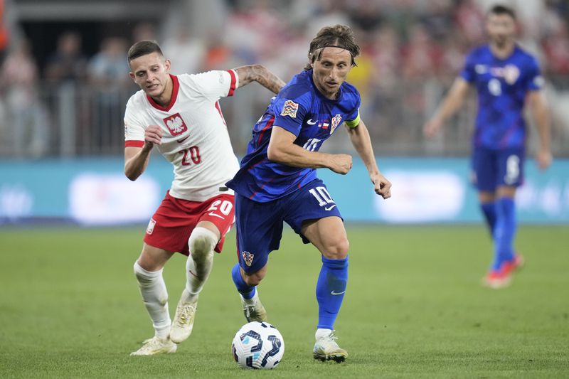 Poland's Sebastian Szymanski, left, challenges for the ball with Croatia's Luka Modric during the UEFA Nations League soccer match between Croatia and Poland at the Opus Arena in Osijek, Croatia, Sunday, Sept. 8, 2024. (AP Photo/Darko Bandic)