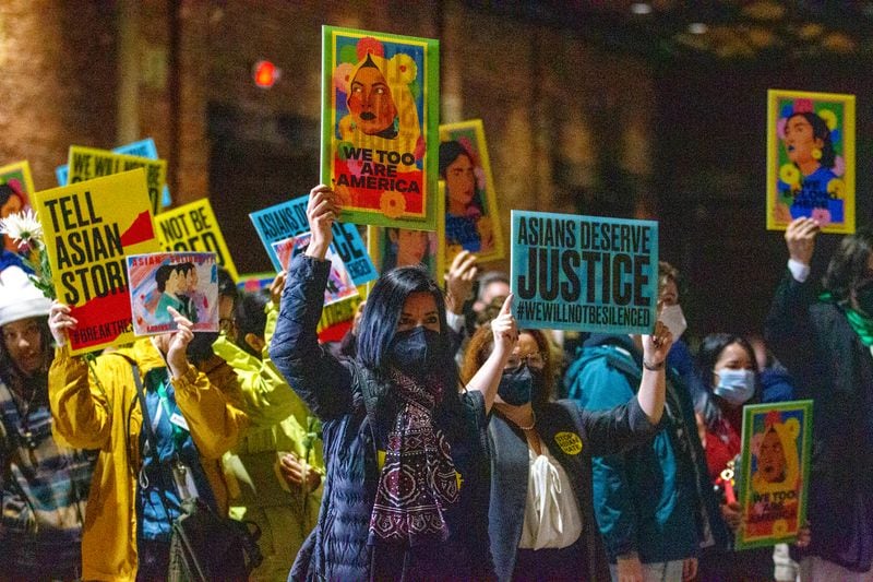 Participants at the Georgia Freight Depot wave signs at the beginning of the Asian Justice 1-year anniversary of the spa shootings rally in Atlanta on March 16, 2022.   STEVE SCHAEFER FOR THE ATLANTA JOURNAL-CONSTITUTION