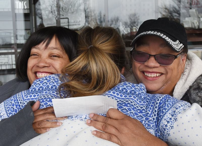 win sisters Priscilla (left) and Patricia Moses gets a hug from Keri Janton, freelance writer and founder of Maximus Janton Foundation, after she presented a gift donation in Norcross on Friday, January 10, 2020. 