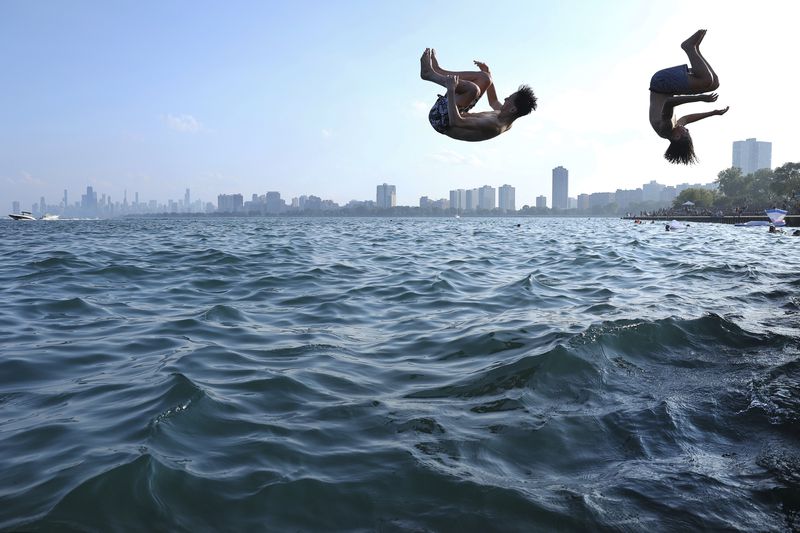 FILE - Two teenagers plunge into Lake Michigan as people cool off during a heat wave at Montrose Beach in Chicago, Aug. 27, 2024. (Chris Sweda/Chicago Tribune via AP, File)