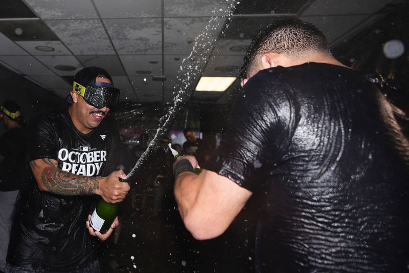 New York Yankees starting pitcher Nestor Cortes, left, sprays champagne on a teammate as they celebrate clinching a playoff spot after a 2-1 win in 10 innings over the Seattle Mariners in a baseball game Wednesday, Sept. 18, 2024, in Seattle. (AP Photo/Lindsey Wasson)