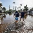 Thomas Chaves, left, and Vinny Almeida walk through floodwaters from Hurricane Helene in an attempt to reach Chaves's mother's house in the Shore Acres neighborhood Friday, Sept. 27, 2024, in St. Petersburg, Fla. (AP Photo/Mike Carlson)