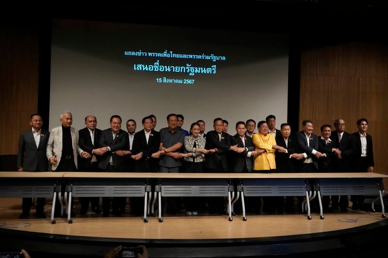 Leader of Pheu Thai Party, Paetongtarn Shinawatra, daughter of Thailand's former Prime Minister Thaksin Shinawatra, eight form left, and coalition partners shake hand during press conference in Bangkok, Thailand, Thursday, Aug. 15, 2024. (AP Photo/Sakchai Lalit)