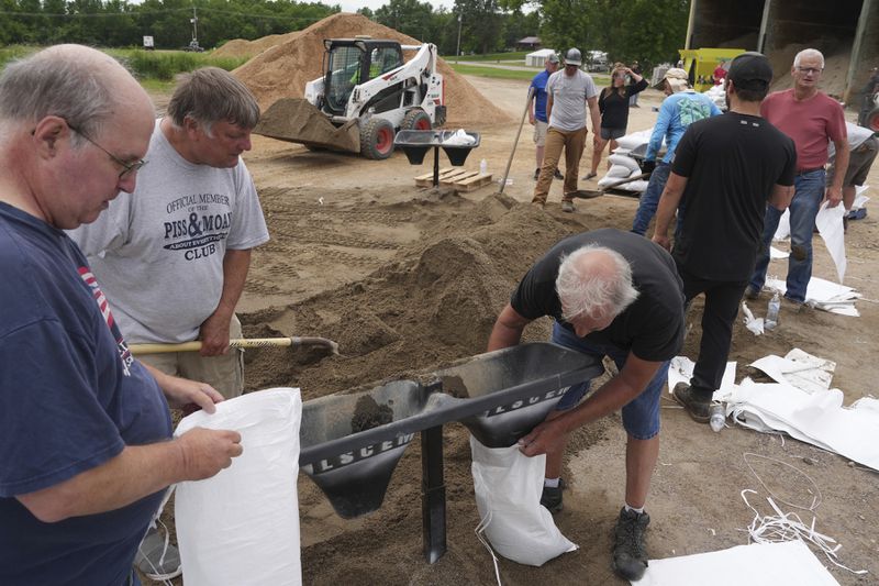 Volunteers help fill sandbags as heavy rains have caused both Tetonka Lake and Sakatah Lake to rise threatening to flood nearby homes and businesses Thursday, June 20, 2024 in Waterville, Minn. (Anthony Souffle/Star Tribune via AP)