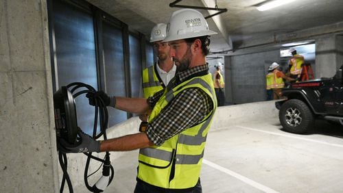 James Miller, EV Charging Consultant Project Manager at EnviroSpark Energy Solutions, holds a 40 amp EV charger at the parking deck of Loews Atlanta Hotel, Friday, June 23, 2023, in Atlanta. (Hyosub Shin / Hyosub.Shin@ajc.com)