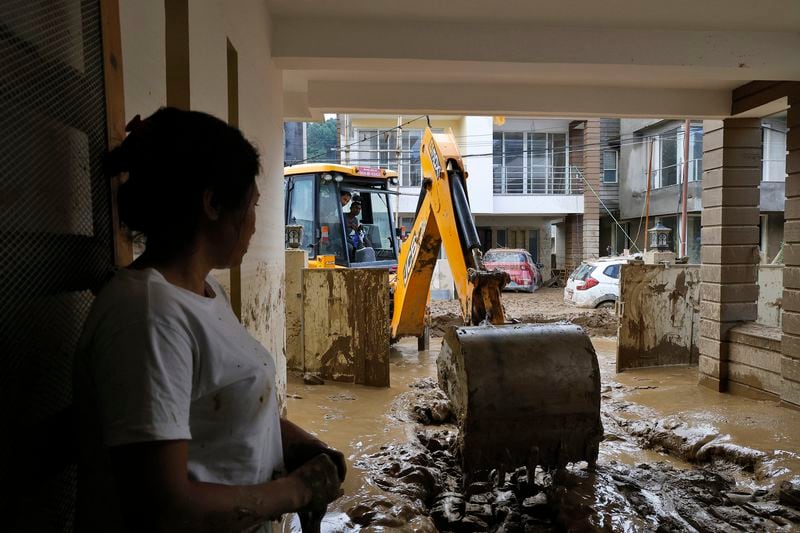 A resident looks on as an earthmover removes mud inside a housing complex in Kathmandu, Nepal, Monday, Sept. 30, 2024 in the aftermath of a flood caused by heavy rains. (AP Photo/Gopen Rai)