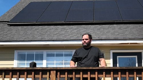 Portrait of Alex Betancourt as solar panels on the roof are shown in background at his home, Friday, March 24, 2023, in Suwanee. Alex Betancourt put solar panels on his roof last year. He received letters from his HOA claiming the panels were an architectural addition that violated the community's rules. Now, they're threatening to remove the panels from his roof. (Hyosub Shin / Hyosub.Shin@ajc.com)