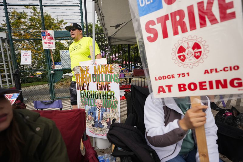 Daniel Dias, a functional test technician who has worked for Boeing for six years, back center, stands near an entrance to the company's factory as workers hold picket signs while striking Tuesday, Sept. 24, 2024, in Renton, Wash. (AP Photo/Lindsey Wasson)