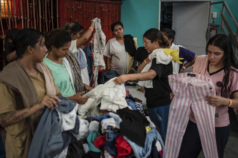 Venezuelan migrants pick out donated clothing at the Peace Oasis of the Holy Spirit Amparito shelter in Villahermosa, Mexico, Friday, June 7, 2024. After the head of Mexico's immigration agency ordered a halt to deportations in December, migrants have been left in limbo as authorities round up migrants across the country and dump them in the southern Mexican cities of Villahermosa and Tapachula. (AP Photo/Felix Marquez)