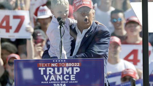 Republican presidential nominee former President Donald Trump holds his grandson Luke Trump as he speaks at a campaign event at Wilmington International Airport in Wilmington, N.C., Saturday, Sept. 21, 2024. (AP Photo/Chris Seward)