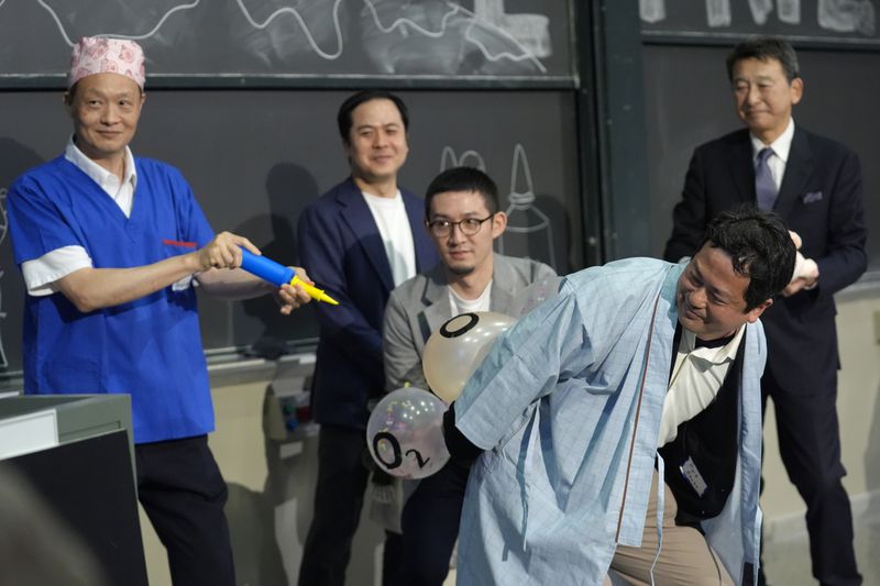 A team of researchers perform a demonstration during a performance showing that many mammals are capable of breathing through their anus while accepting the 2024 Ig Nobel prize in physiology at the Ig Nobel Prize ceremony at Massachusetts Institute of Technology, in Cambridge, Mass., Thursday, Sept. 12, 2024. (AP Photo/Steven Senne)