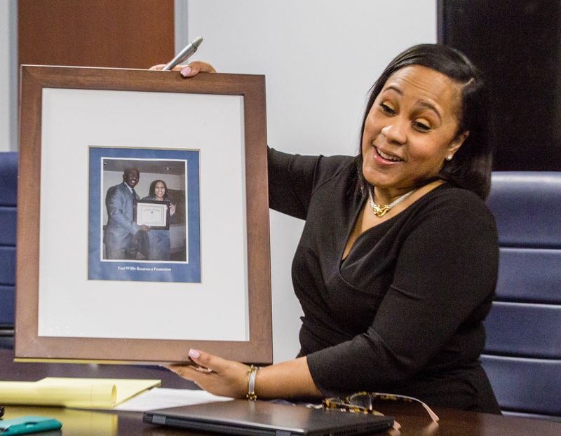 Fulton County's newly elected District Attorney Fani Willis shows the photo left behind by former DA Paul Howard, who was once her boss, in a conference room at the Fulton County Courthouse in downtown Atlanta on Thursday, Feb 18, 2021. The former DA and his team took all the furniture and left behind boxes of unprocessed cases and 10,000 open cases dating back to 2017.  (Jenni Girtman for The Atlanta Journal-Constitution)