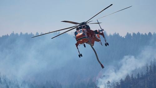 A helicopter heads in for a water drop as the Quarry wildfire burns in the foothills near the Ken Caryl Ranch development Thursday, Aug. 1, 2024, southwest of Littleton, Colo. (AP Photo/David Zalubowski)