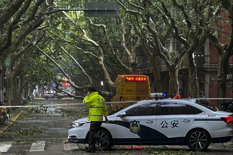 Policemen closed a road as fallen trees along a street in the aftermath of Typhoon Bebinca in Shanghai, China, Monday, Sept. 16, 2024. (Chinatopix Via AP)