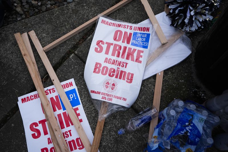 Extra picket signs sit on the sidewalk as Boeing workers strike after union members voted to reject a contract offer, Sunday, Sept. 15, 2024, near the company's factory in Everett, Wash. (AP Photo/Lindsey Wasson)