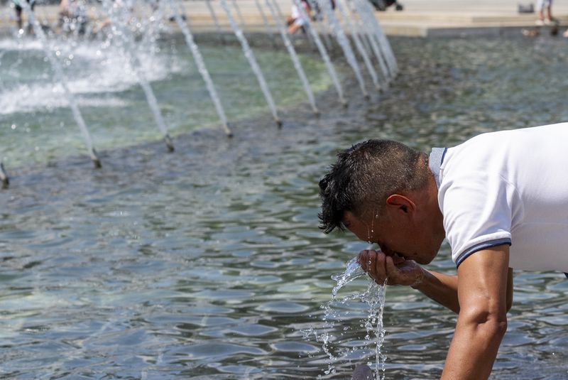 Jose Solano, from Venezuela, splashes water on his face from the Rainbow Pool at the World War II Memorial, Friday, June 21, 2024, in Washington. Temperatures are forecast to reach 100 degrees on Saturday. (AP Photo/Alex Brandon)