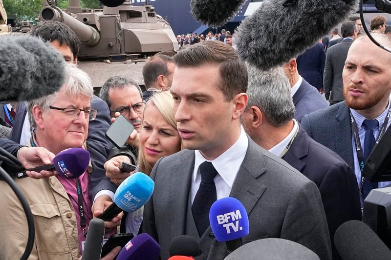 Jordan Bardella, president of the far-right National Front party, answers reporters after visiting the Eurosatory Defense and Security exhibition, Wednesday, June 19, 2024 in Villepinte, north of Paris. Jordan Bardella, hoping to become France's prime minister, appealed Tuesday to voters to hand his party a clear majority after French President Emmanuel Macron's announcement on June 9 that he was dissolving France's National Assembly, parliament's lower house.( AP Photo/Michel Euler)