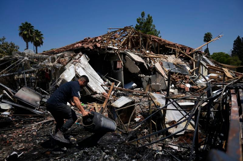 A man works next to a destroyed home after rockets struck in Katzrin, in the Israeli-annexed Golan Heights, Wednesday, Aug. 21, 2024. Lebanon's Hezbollah has launched more than 50 rockets, hitting a number of private homes in the area.(AP Photo/Ariel Schalit)