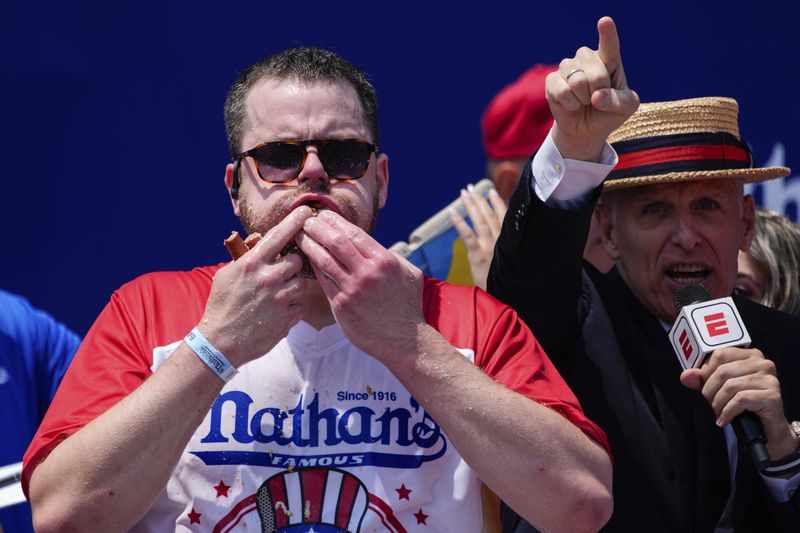 Patrick Bertoletti stuffs hot dogs into his mouth during the men's division in Nathan's Famous Fourth of July hot dog eating contest, Thursday, July 4, 2024, at Coney Island in the Brooklyn borough of New York. Bertoletti ate 58 hot dogs. (AP Photo/Julia Nikhinson)