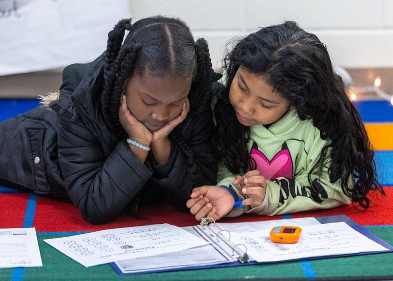 Kimberly Elementary School third graders Joslyn Harris (left) and Dulce Ozuna read out loud to each other during reading class on Tuesday, Dec. 5, 2023. They set a timer, see how long it takes them to read a passage and record it on paper. Click below to hear the audio. (Steve Schaefer/steve.schaefer@ajc.com)