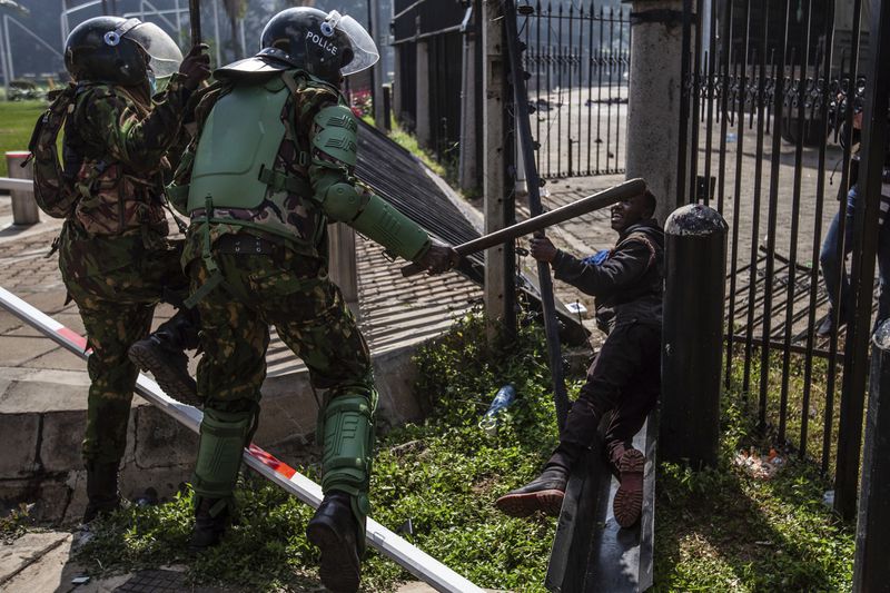 Police beat a protester inside the Kenyan parliament compound during a protest over proposed tax hikes in a finance bill in downtown Nairobi, Kenya, Tuesday, June 25, 2024 (AP Photo/Samson Otieno)