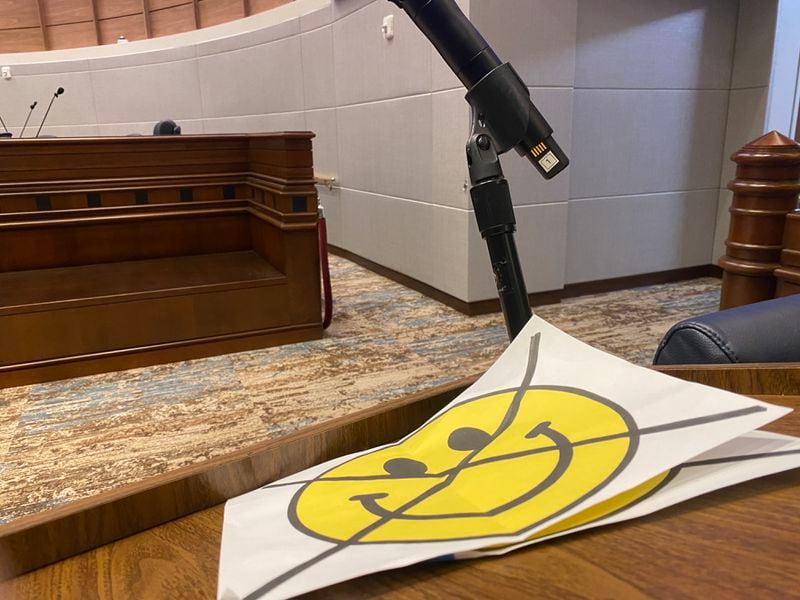 Some of the 75 demonstrators who attended the Wednesday, Jan. 19 meeting of the Fulton County Commission meeting brought these signs to of a crossed-out smiley face asking commissioners not to extend a staff contract with a temporary staffing agency named Happy Faces. (Ben Brasch/AJC)