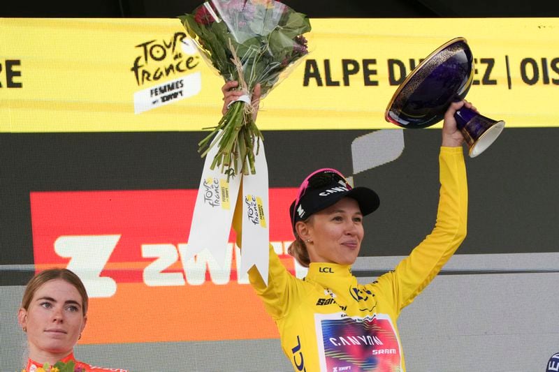 Tour de France winner Katarzyna Niewiadoma of Poland, wearing the overall leader's yellow jersey, celebrates next to second place Demi Vollering of The Netherlands, left, on the podium after the eighth stage of the Tour de France Women cycling race with start in Le Grand-Bornand and finish in Alpe d'Huez, France, Sunday, Aug. 18, 2024. (AP Photo/Peter Dejong)