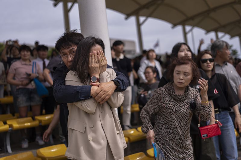 Yeon Soo Lee, 55, a kitchenware business owner from Gangneung, comforts his sobbing wife, Sun Young Kim, as they watch their son leave the training ground and head to his barracks after an induction ceremony at a Marine base in Pohang, South Korea, Monday, May 27, 2024. (AP Photo/Jae C. Hong)