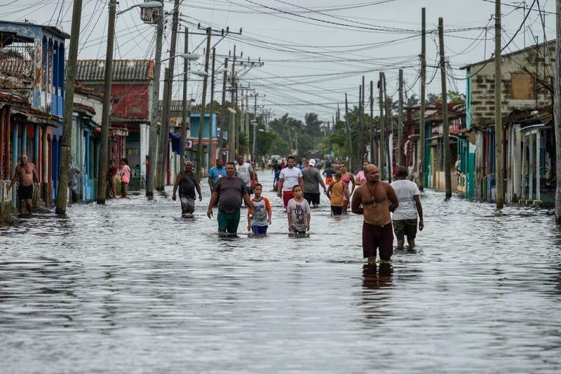 Residents wade through a street flooded in the passing of Hurricane Helene, in Batabano, Mayabeque province, Cuba, Thursday, Sept. 26, 2024. (AP Photo/Ramon Espinosa)